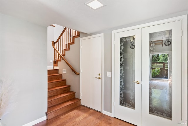 foyer entrance with stairway, french doors, light wood-type flooring, and baseboards