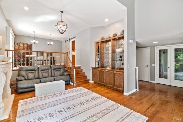 living room with a barn door, wood finished floors, a notable chandelier, and recessed lighting