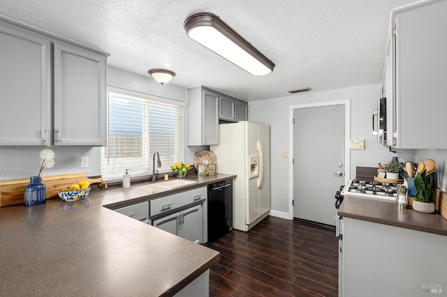 kitchen with white refrigerator with ice dispenser, dark countertops, dishwasher, and visible vents