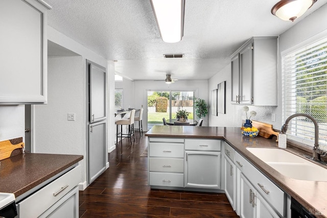 kitchen with a sink, ceiling fan, visible vents, a peninsula, and a textured ceiling