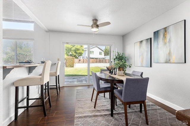 dining area with dark wood-type flooring, a healthy amount of sunlight, ceiling fan, and baseboards