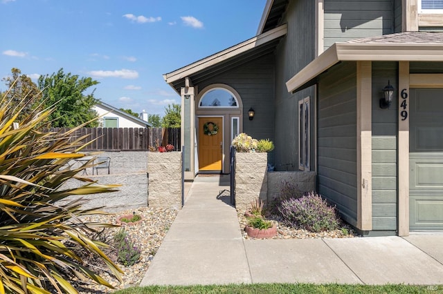 doorway to property with a garage and fence