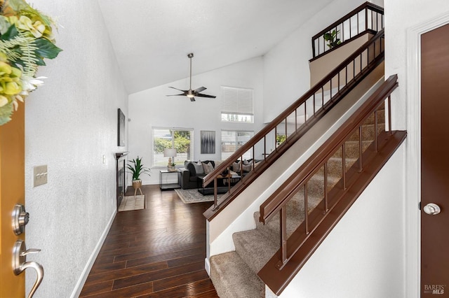 interior space featuring ceiling fan, high vaulted ceiling, stairs, baseboards, and hardwood / wood-style flooring
