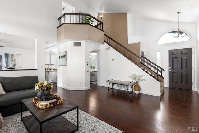 living room with visible vents, hardwood / wood-style flooring, stairs, and a towering ceiling