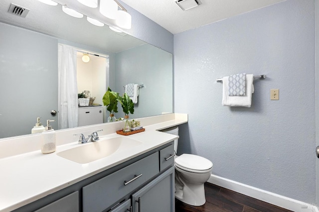 bathroom featuring toilet, visible vents, wood finished floors, and baseboards