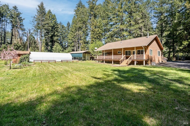 back of house with a lawn, an outdoor structure, a carport, and a wooden deck