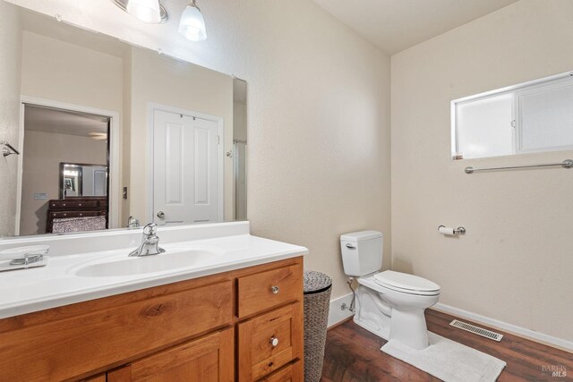 bathroom with vanity, toilet, visible vents, baseboards, and wood finished floors