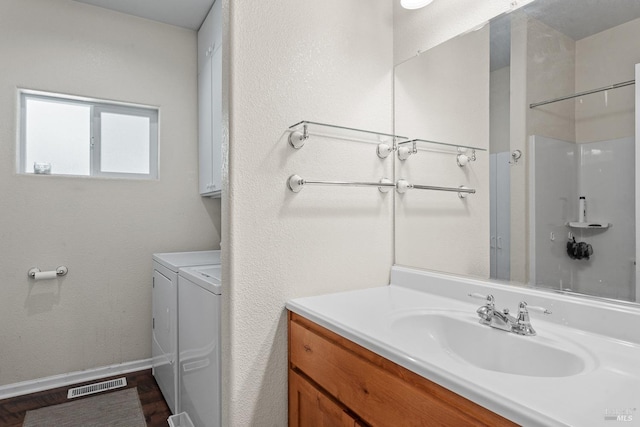 bathroom with a shower, visible vents, baseboards, washer and dryer, and vanity