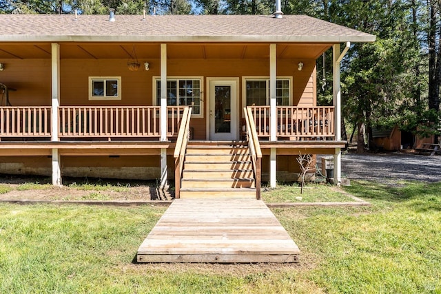property entrance with roof with shingles, covered porch, and a yard