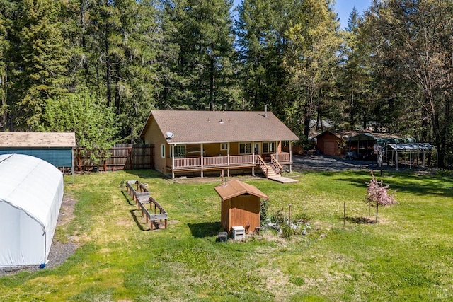 back of house featuring a wooden deck, an outbuilding, a storage shed, a lawn, and fence