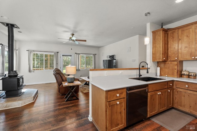 kitchen featuring a wood stove, a sink, open floor plan, dishwasher, and a peninsula
