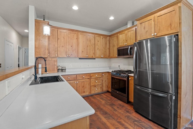 kitchen featuring recessed lighting, stainless steel appliances, light countertops, a sink, and dark wood-type flooring