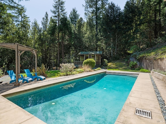 outdoor pool with fence, an outbuilding, a storage structure, and a patio area