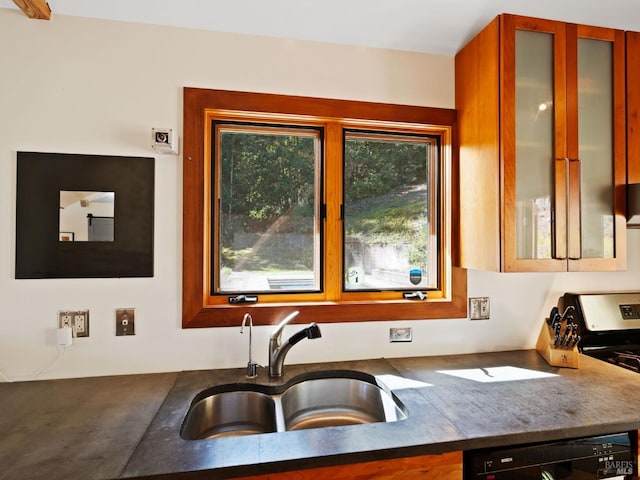 kitchen featuring glass insert cabinets, a sink, dark countertops, black dishwasher, and stainless steel stove