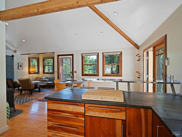 kitchen featuring vaulted ceiling with beams, open floor plan, and a healthy amount of sunlight