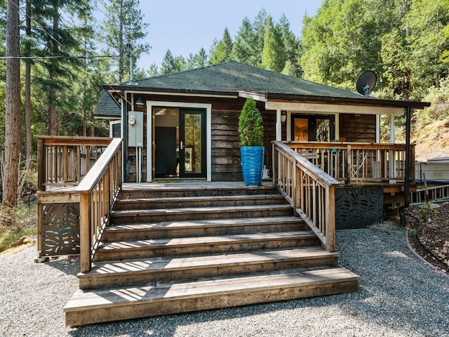 exterior space with stairway, covered porch, and roof with shingles