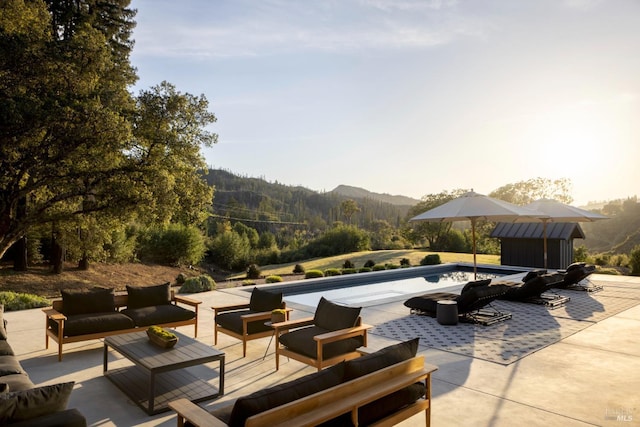 view of patio with an outdoor living space, a mountain view, and an outdoor pool