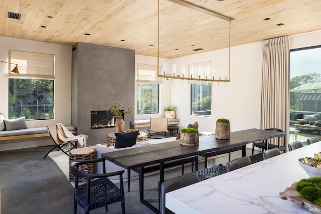 dining space featuring concrete flooring, visible vents, wood ceiling, and a fireplace