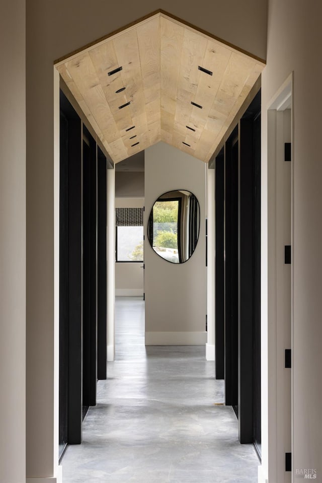 hall with baseboards and vaulted ceiling