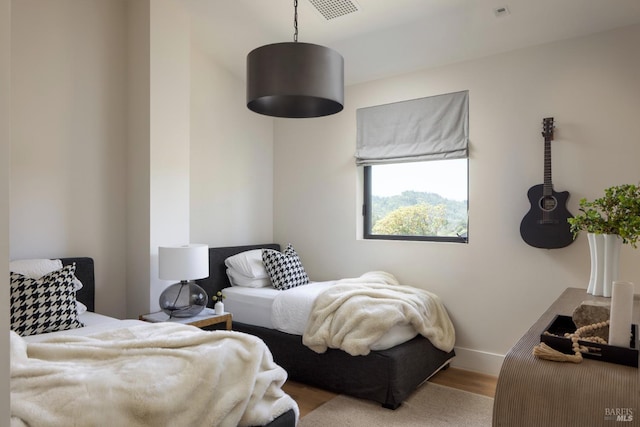 bedroom with visible vents, baseboards, and wood finished floors