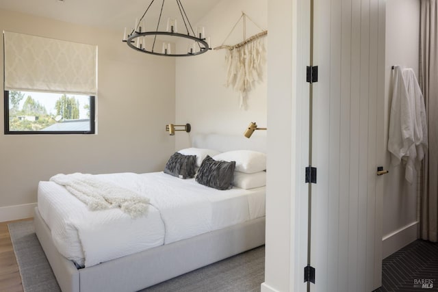 bedroom featuring baseboards, wood finished floors, and a chandelier