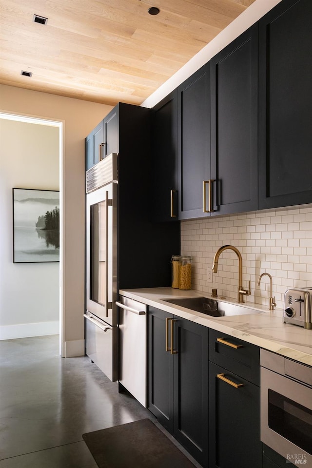kitchen featuring a sink, built in appliances, dark cabinets, finished concrete floors, and tasteful backsplash