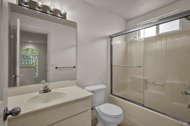 full bathroom featuring bath / shower combo with glass door, toilet, and vanity