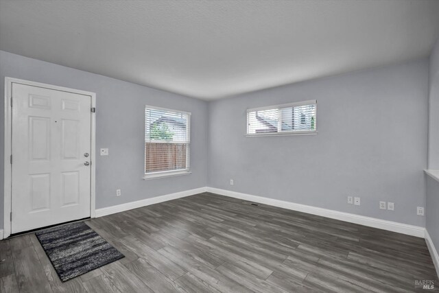 foyer entrance with baseboards and dark wood-style flooring