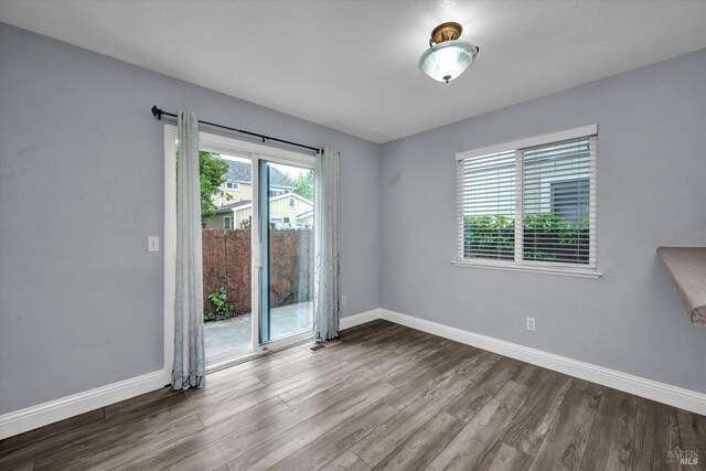 empty room featuring visible vents, wood finished floors, and baseboards