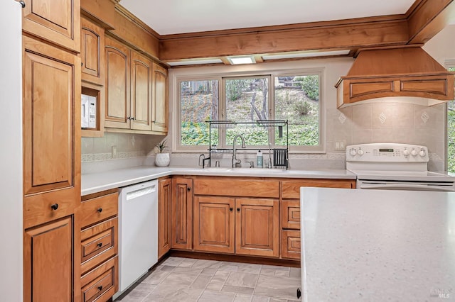 kitchen with custom exhaust hood, light countertops, a sink, and white appliances