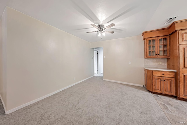 interior space featuring light colored carpet, visible vents, ceiling fan, and baseboards