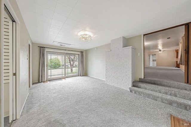 unfurnished living room with baseboards, ceiling fan, stairs, and carpet flooring
