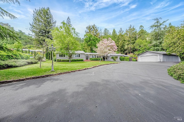 single story home featuring an outbuilding, a detached garage, and a front lawn