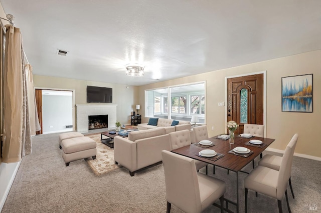 living room with baseboards, visible vents, light colored carpet, and a brick fireplace