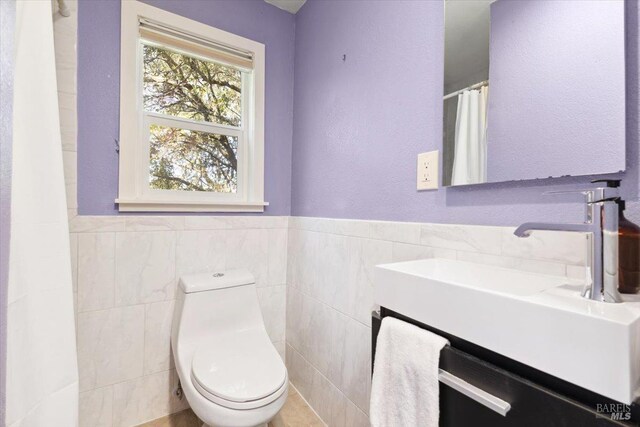 full bath with toilet, a wainscoted wall, tile walls, and curtained shower