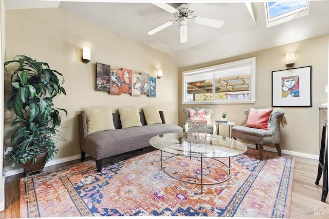 living room with lofted ceiling with skylight, a ceiling fan, wood finished floors, and baseboards