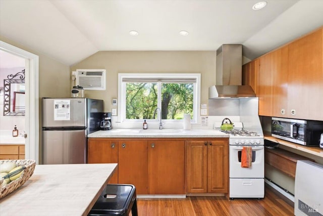 kitchen featuring a sink, wall chimney exhaust hood, vaulted ceiling, light countertops, and appliances with stainless steel finishes