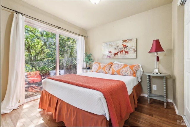 bedroom with wood finished floors, access to outside, and baseboards