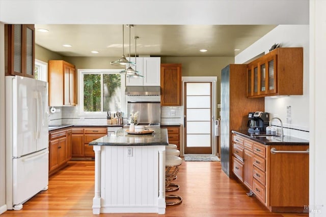 kitchen featuring decorative backsplash, light wood finished floors, freestanding refrigerator, and a sink