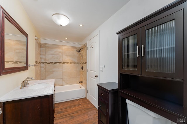 bathroom with vanity, toilet, wood finished floors, and tub / shower combination