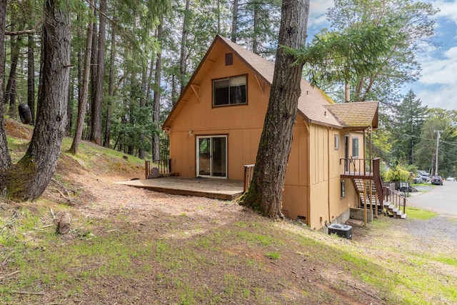 back of house with a wooden deck and roof with shingles