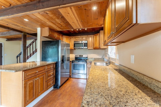 kitchen featuring appliances with stainless steel finishes, light stone countertops, brown cabinets, a sink, and wooden ceiling