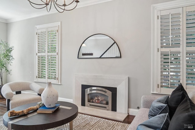 living area with a chandelier, wood finished floors, a healthy amount of sunlight, and crown molding