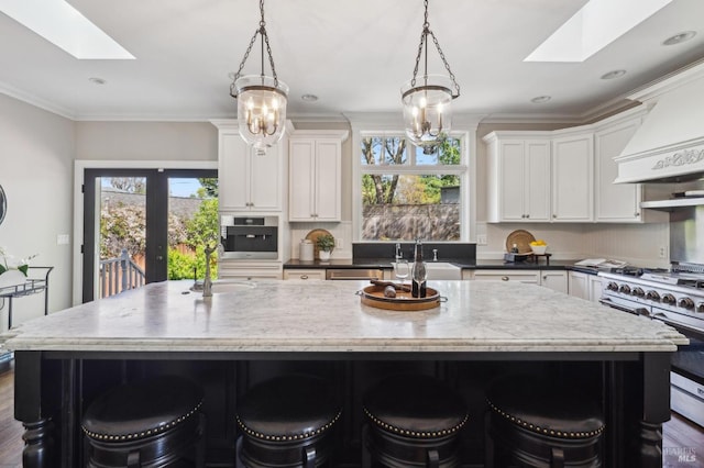 kitchen with a skylight, a sink, appliances with stainless steel finishes, and white cabinetry