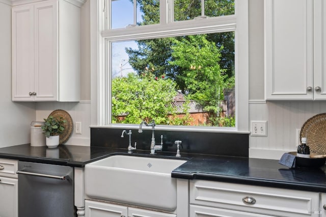 kitchen with dark countertops, white cabinets, and a sink