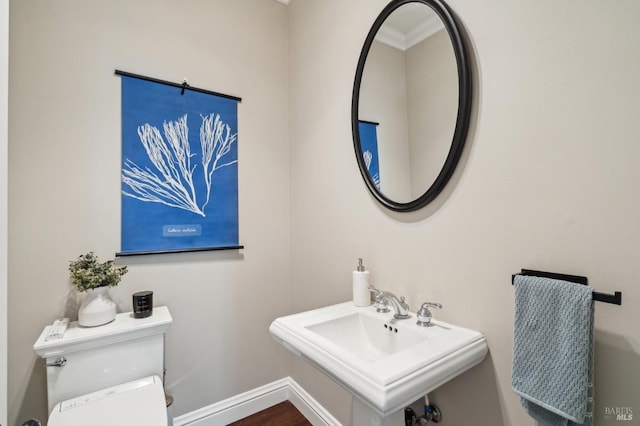 half bath featuring baseboards, toilet, and a sink