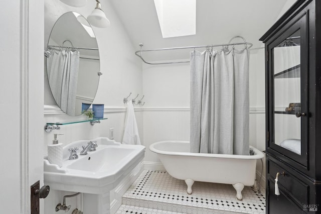 bathroom with a sink, a shower with shower curtain, tile patterned floors, a freestanding bath, and a skylight