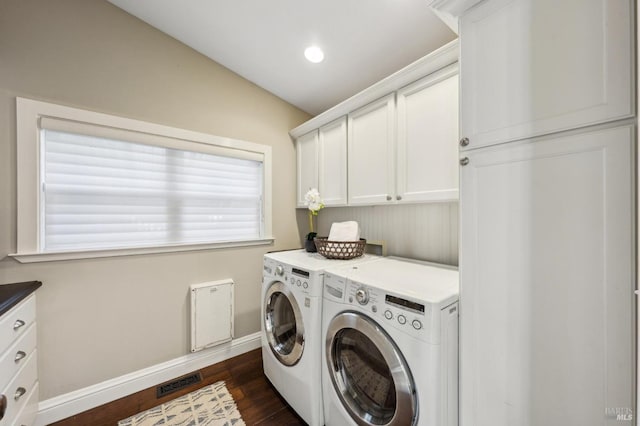 washroom with washing machine and dryer, visible vents, baseboards, cabinet space, and dark wood-type flooring