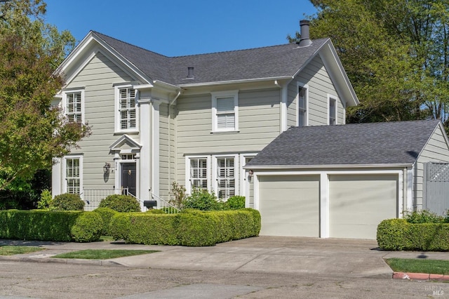 view of front facade with a shingled roof, driveway, and an attached garage