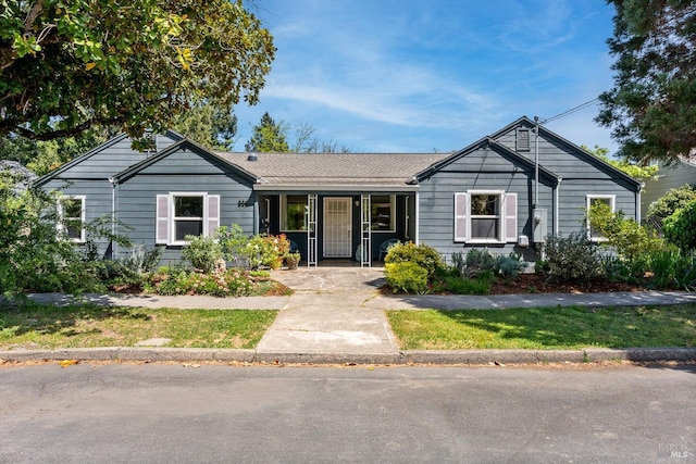 ranch-style home featuring a front lawn and a shingled roof